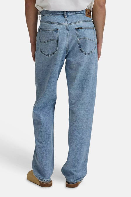Jeans en denim bleu clair de Lee, poches arrière avec surpiqûres, étiquette en cuir à la taille, portées avec des sabots marron.