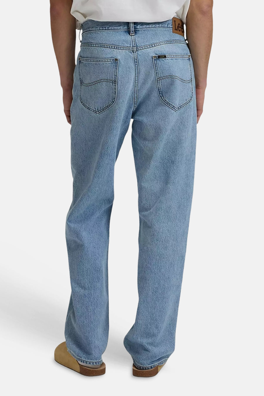 Jeans en denim bleu clair de Lee, poches arrière avec surpiqûres, étiquette en cuir à la taille, portées avec des sabots marron.
