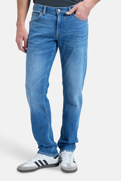 Jean droit bleu de Lee, avec poches arrière et chaussures blanches.