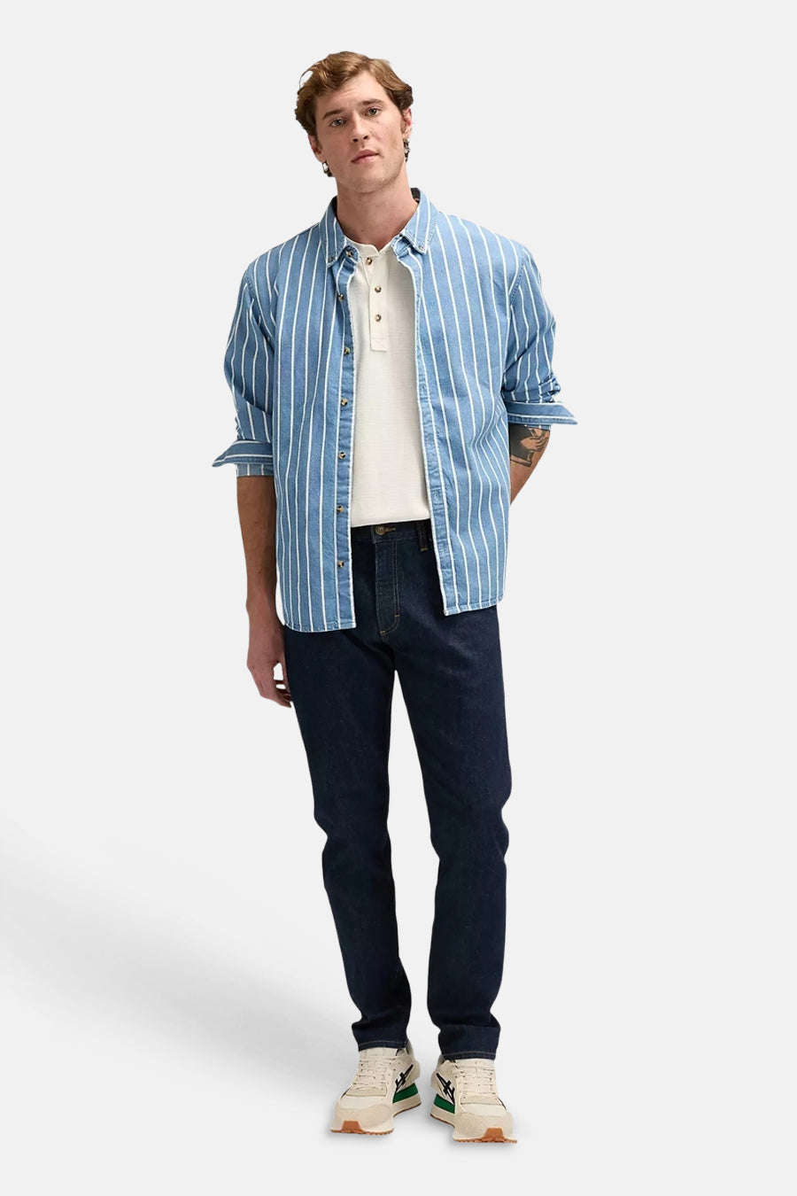 Donkere blauwe tapered jeans van Lee®, met strakke pasvorm, gedragen met gestreept overhemd en witte sneakers, front view.