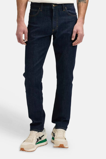 Donkerblauwe tapered jeans van Lee®, met klassieke vijfzakkenstijl en subtiele slijtage, vooraanzicht op model met witte sneakers.