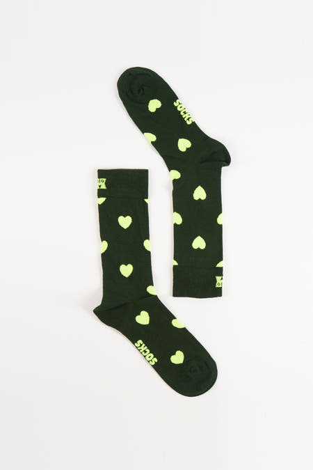 Chaussettes vertes de Happy Socks avec un imprimé cœur jaune clair sur un fond blanc.