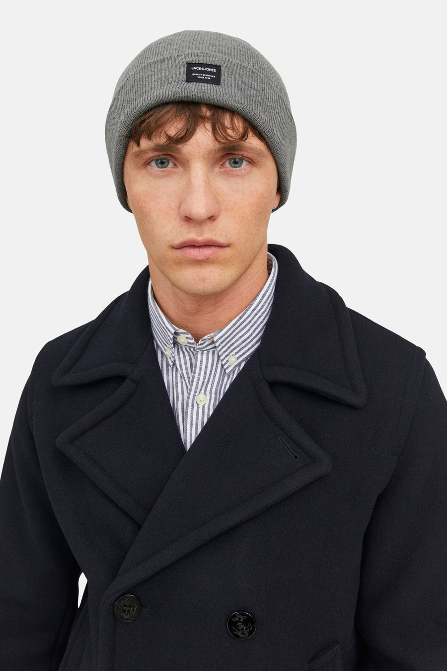 Chapeau gris d'ACCESSORIES BY JACK & JONES, porté avec un chemisier rayé et une veste double boutonnée bleu marine.