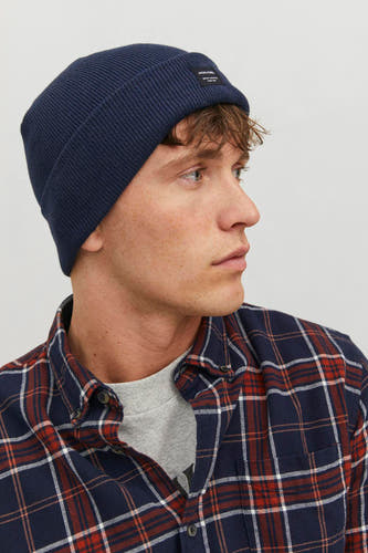 Chapeau bleu de Jack & Jones, porté avec un chemisier à carreaux et une chemise grise.