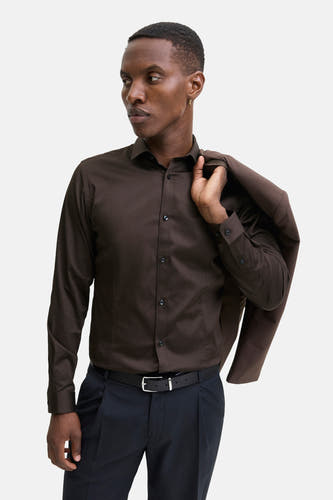 Chemise brune à manches longues de PREMIUM by JACK & JONES, avec un manteau brun sur l'épaule et un pantalon noir.