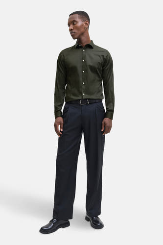 Chemise verte à manches longues de PREMIUM by JACK & JONES, avec des boutons blancs et portée avec un pantalon noir et une ceinture.