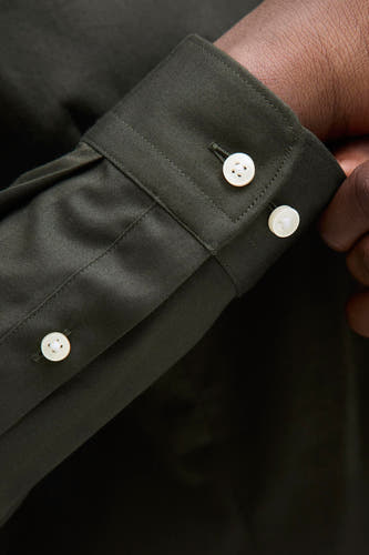 Chemise verte à manches longues de PREMIUM by JACK & JONES, gros plan d'une manche avec des boutons blancs.