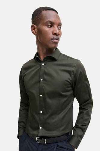 Chemise verte à manches longues de PREMIUM by JACK & JONES, avec des boutons blancs et portée avec une ceinture noire.
