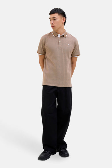 Polo marron à manches courtes de PREMIUM par JACK & JONES, avec des accents blancs au col et aux manches, porté avec un pantalon noir.