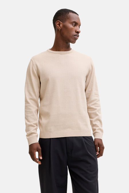 Man met beige trui en zwarte broek.