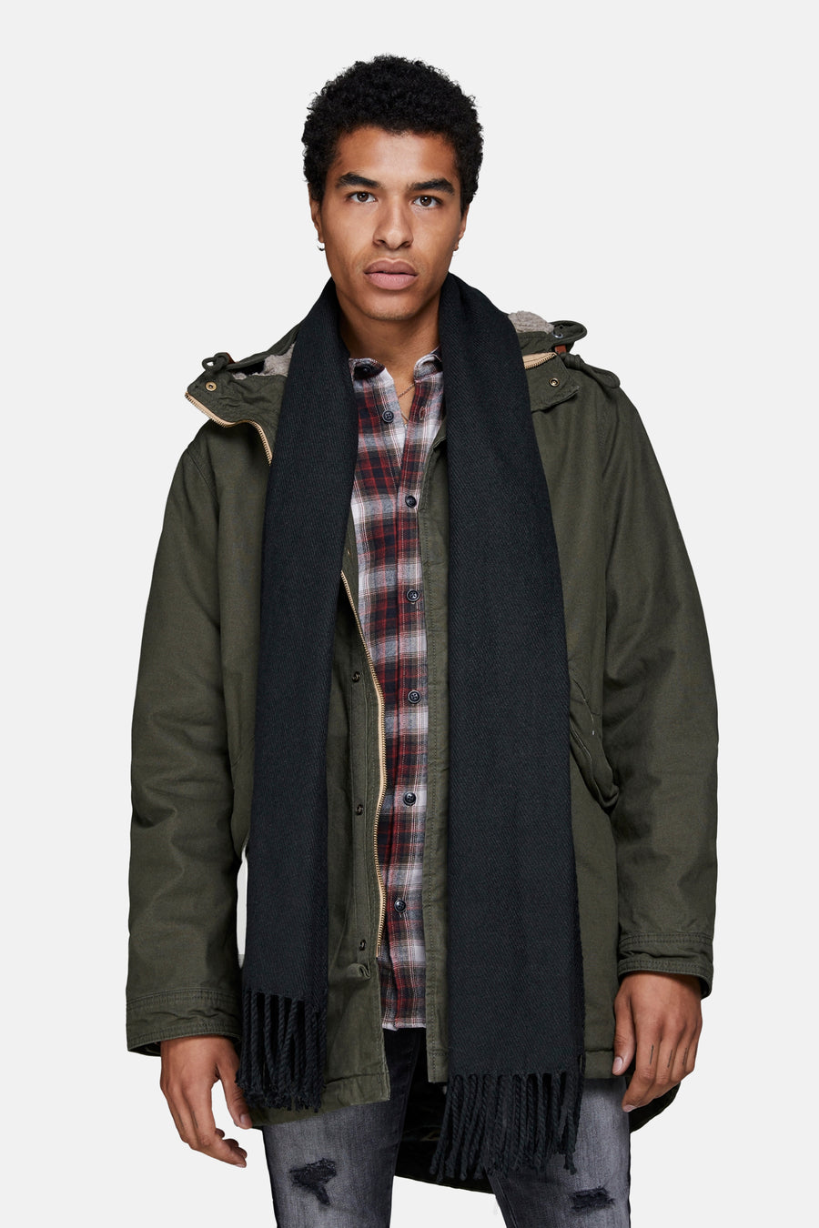 Chapeau d'hiver noir d'ACCESSORIES BY JACK & JONES, avec franges, porté avec un chemisier à carreaux et une parka.