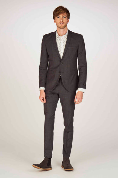 Homme en manteau gris avec un chemise blanc et des chaussures brunes, debout.