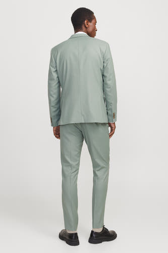 Pantalon de costume vert vert PRE PREMI by by & J,, vu vu de derrière, avec des chaussures noires et des chaussettes beige.