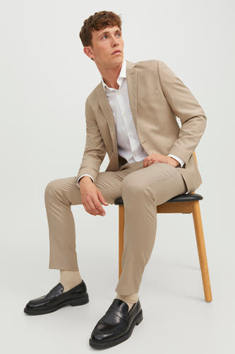 Pantalon de costume beige PREMIUM by JACK & JONES, porté avec un chemisier blanc, des loafers noirs et des chaussettes beige.