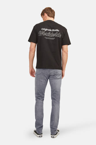 Jean slim fit gris clair de JACK & JONES, vu de derrière, associé à un T-shirt noir et des baskets.