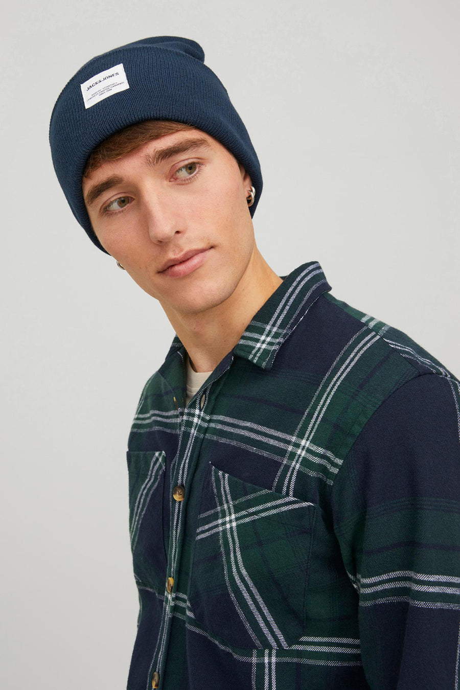 Casquette bleue d'ACCESSORIES BY JACK & JONES, avec un étiquette et portée avec une chemise à carreaux.