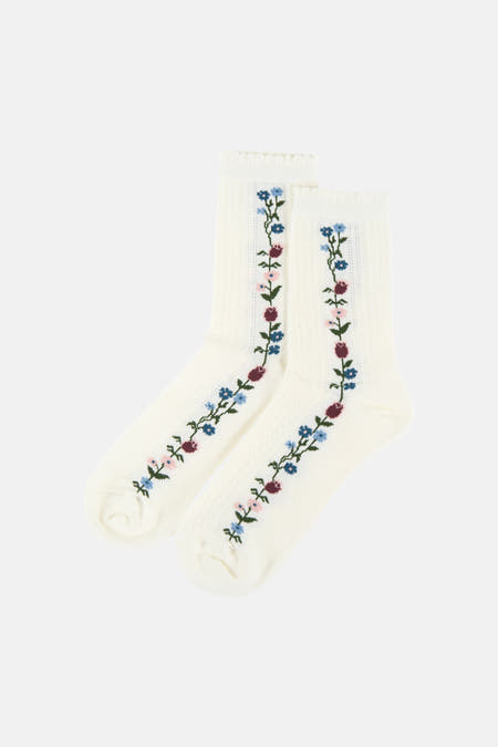 Twee witte sokken van BIRDLAND met verticale bloemenborduursels in blauw, roze, bordeaux en groen.