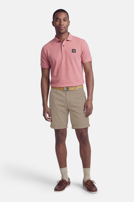 Grijze short van JACK & JONES JEANS INTELLIGENCE, met opgerolde pijpen, gecombineerd met een roze polo, riem en bruine bootschoenen.