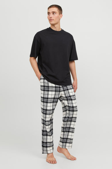 Pantalon de pyjama noir et blanc d'ACCESSORIES BY JACK & JONES, à motif à carreaux, porté avec un t-shirt noir.