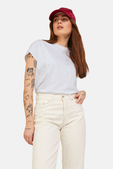 T-shirt blanc à manches courtes de JJXX, porté avec un chapeau bordeaux et des longs cheveux bruns.