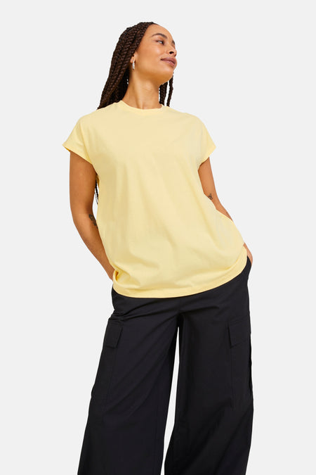 T-shirt jaune de JJXX, porté avec une veste en jean et un pantalon noir ample à poches cargo.