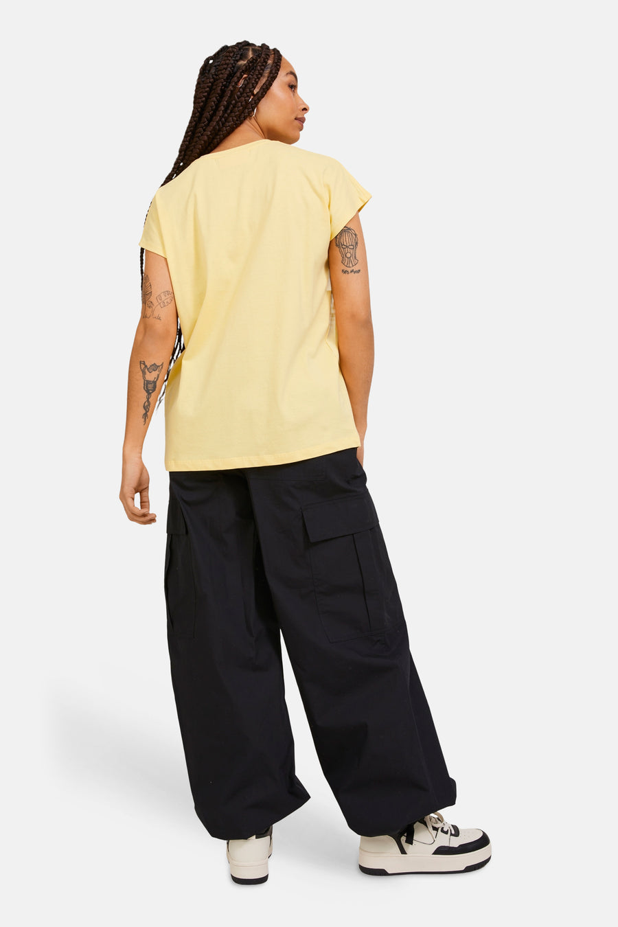 T-shirt jaune de JJXX, à manches courtes, porté avec un pantalon cargo noir ample et des baskets, dos.