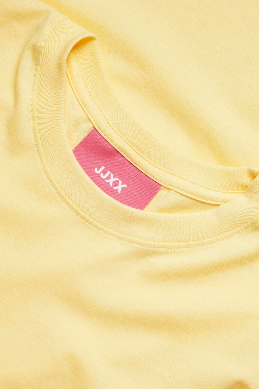 T-shirt jaune de JJXX, gros plan de l'encolure avec une étiquette rose.