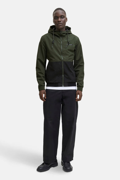 Veste de pluie verte d'ORIGINALS BY JACK & JONES, avec une couleur unie noire, capuchon avec cordon de serrage, et portée sur un T-shirt blanc et un pantalon noir.