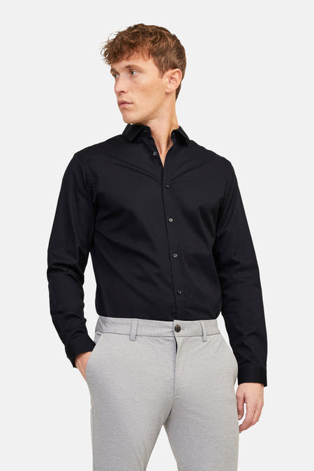 Chemise noire de PREMIUM by JACK & JONES, à manches longues, portée avec un pantalon gris et des chaussures noires.