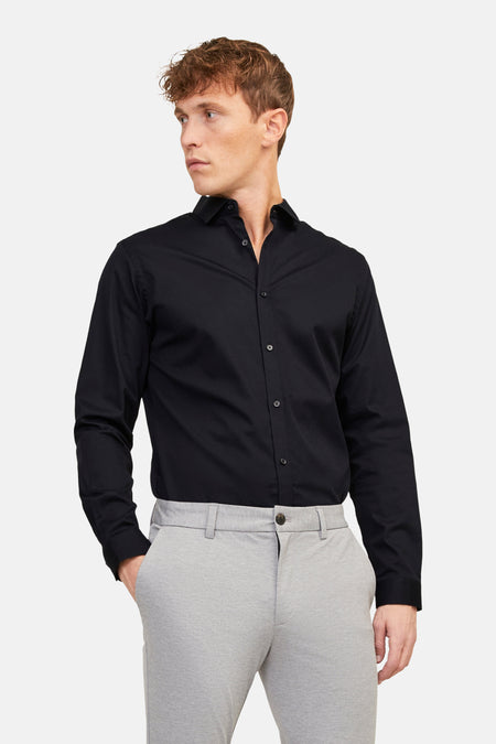 Chemise noire de PREMIUM by JACK & JONES, à manches longues, portée avec un pantalon gris et des chaussures noires.
