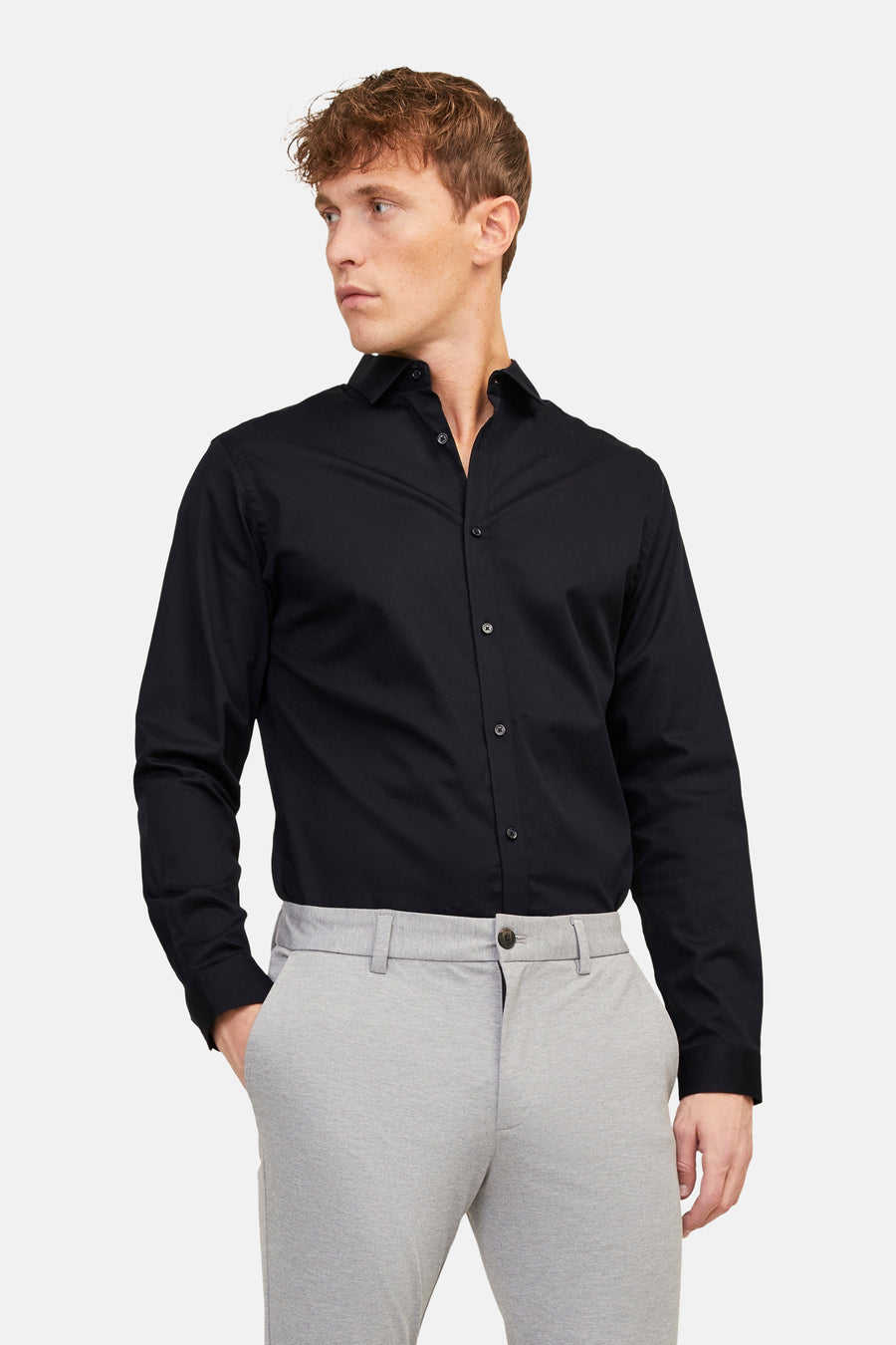 Chemise noire de PREMIUM by JACK & JONES, à manches longues, portée avec un pantalon gris et des chaussures noires.