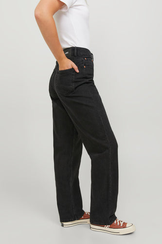 Vrouw in zwarte jeans en bruine Converse sneakers.