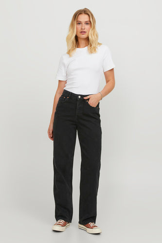 Vrouw met wit T-shirt en zwarte jeans, bruine Converse sneakers.