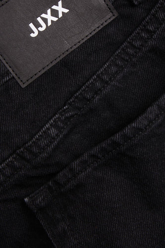 Zwarte jeans met JJXX-label, close-up.
