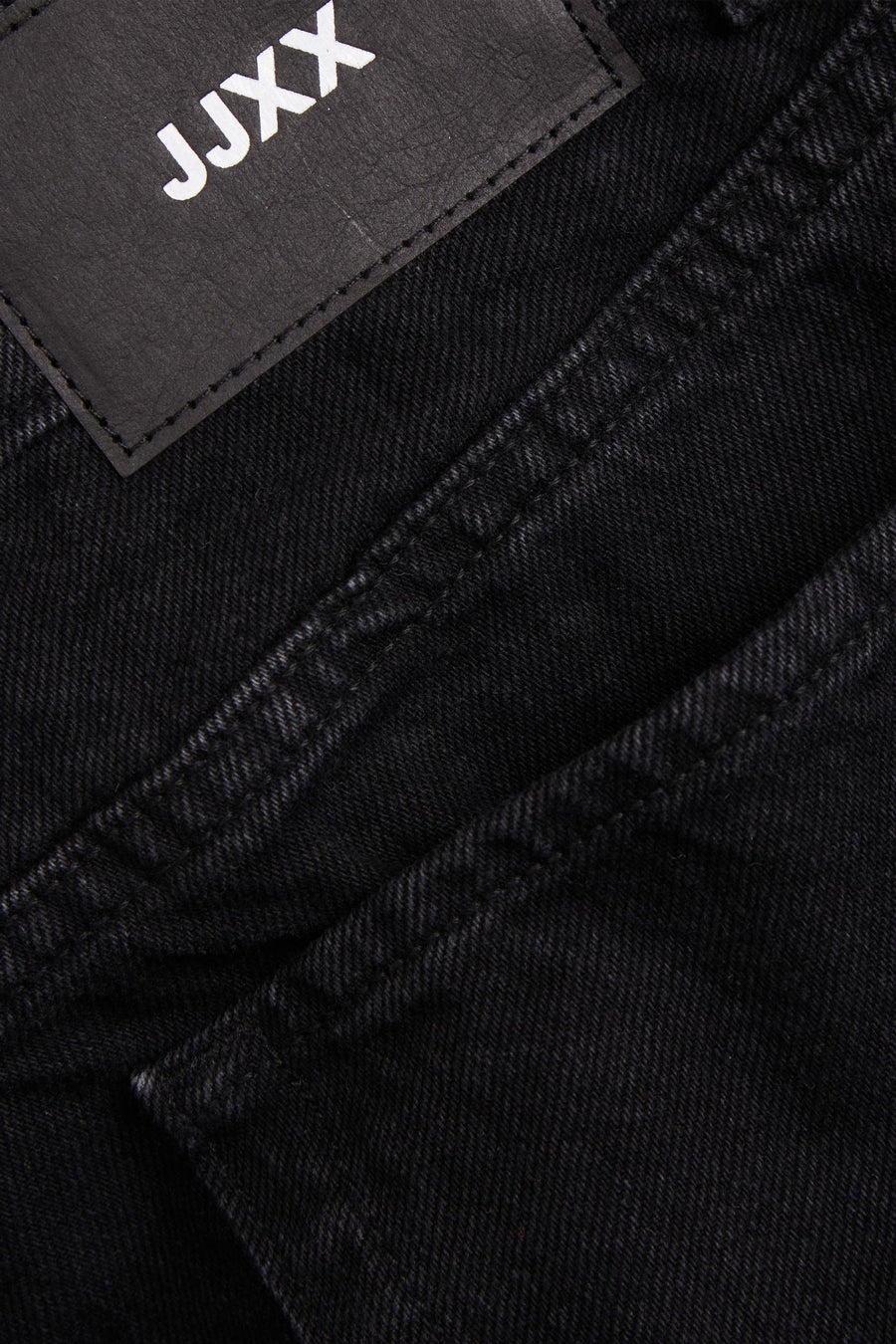 Zwarte jeans met JJXX-label, close-up.
