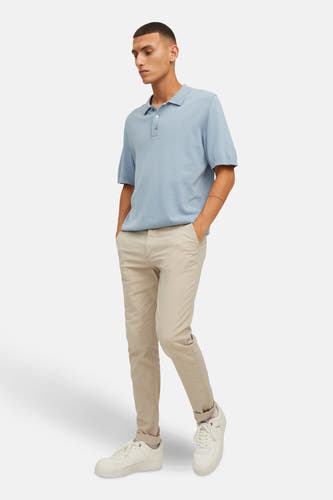 Beige chino van JACK & JONES JEANS INTELLIGENCE, gecombineerd met een lichtblauw poloshirt en witte sneakers.