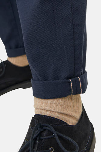 Jean chino bleu de JACK & JONES JEANS INTELLIGENCE, avec des poches de pantalon relevées et des chaussettes brunes, associé à des chaussures noires.