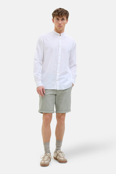 Groene short van JACK & JONES JEANS INTELLIGENCE, gecombineerd met een wit overhemd met lange mouwen en beige sneakers.