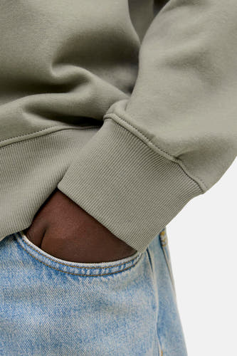 Gilet de coton de CORE BY JACK & JONES, avec des manches raglées et une main dans un sac à dos bleu.