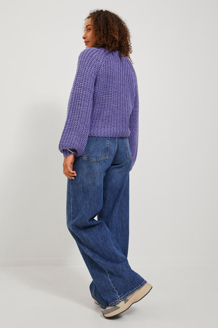 Pull noir de JJXX, avec des manches longues, associé à des jeans bleus et des baskets.