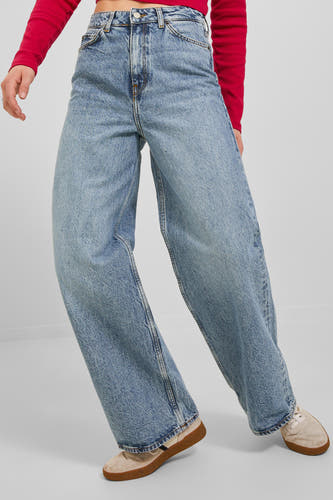 Jean large en denim bleu de JJXX, porté avec un haut rouge et des chaussures de couleur crème.