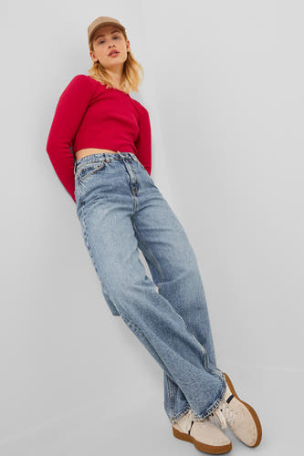 Jean large en denim bleu de JJXX, avec un chemisier rouge et des baskets beige.