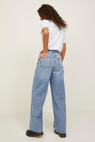 Blauwe denim jeans wide van JJXX, met zakken en gedragen met een wit T-shirt en zwarte schoenen.
