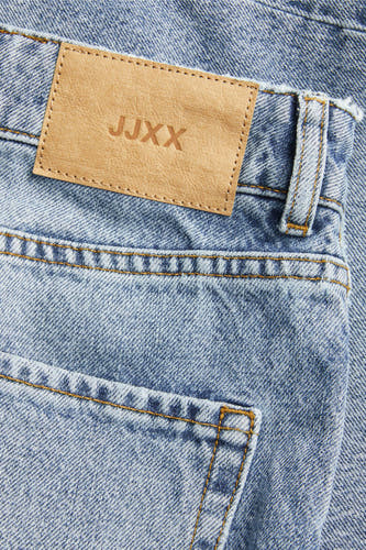 Jean large en denim bleu moyen de JJXX, avec une étiquette de marque en cuir brun à l'arrière et des coutures orange.