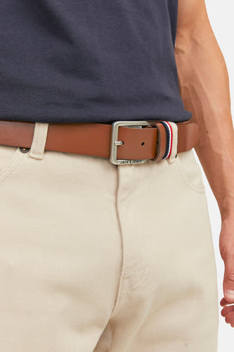 Ceinture marron d'ACCESSORIES BY JACK & JONES avec boucle argentée et accents rouge-blanc-bleu, portée avec un pantalon beige et une chemise bleu foncé.