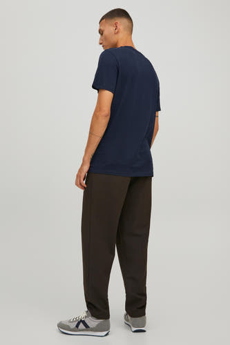 T-shirt bleu de CORE BY JACK & JONES, avec manches courtes et porté avec un pantalon brun et des baskets grises.