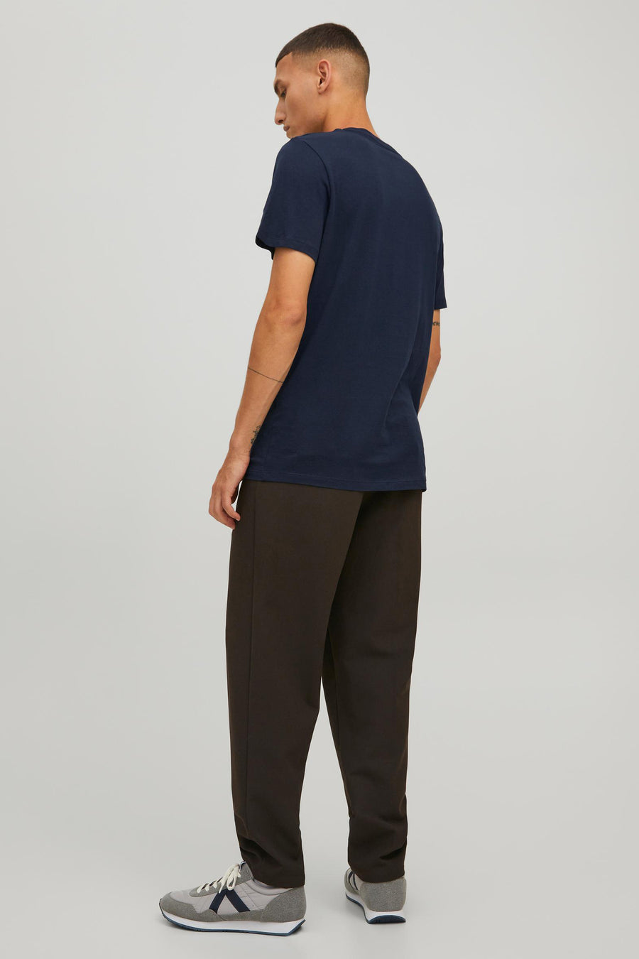 T-shirt bleu de CORE BY JACK & JONES, avec manches courtes et porté avec un pantalon brun et des baskets grises.