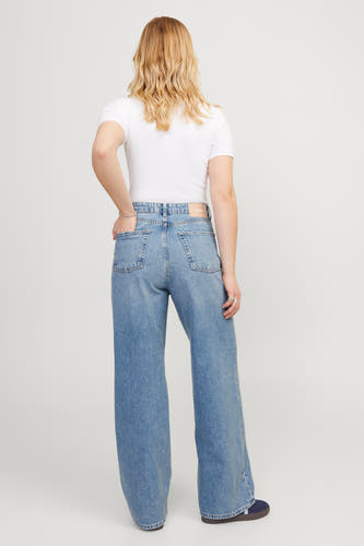 Jean bleu moyen JJXX, vu de derrière, avec un shirt blanc et des chaussures noires.