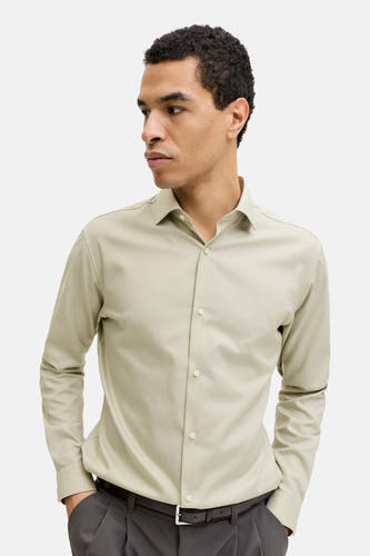 Chemise verte à manches longues de PREMIUM by JACK & JONES, avec col boutonné et manches longues, portée avec un pantalon foncé.
