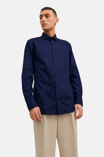 Chemise homme bleue à manches longues de PREMIUM by JACK & JONES, portée avec un pantalon beige.